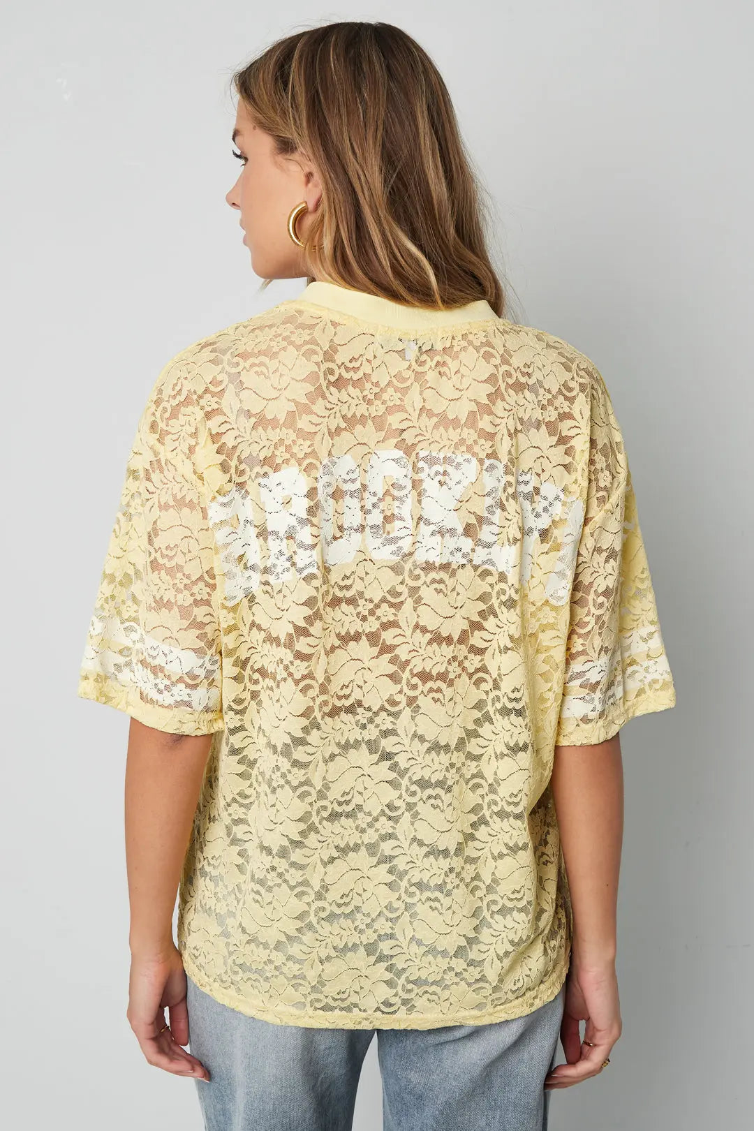 Aanfoto achterkant gele V-hals kant Amerikaanse T-shirt. De T-shirt is voorzien van een elegante kanten afwerking langs de halslijn en comfortabele pasvorm.