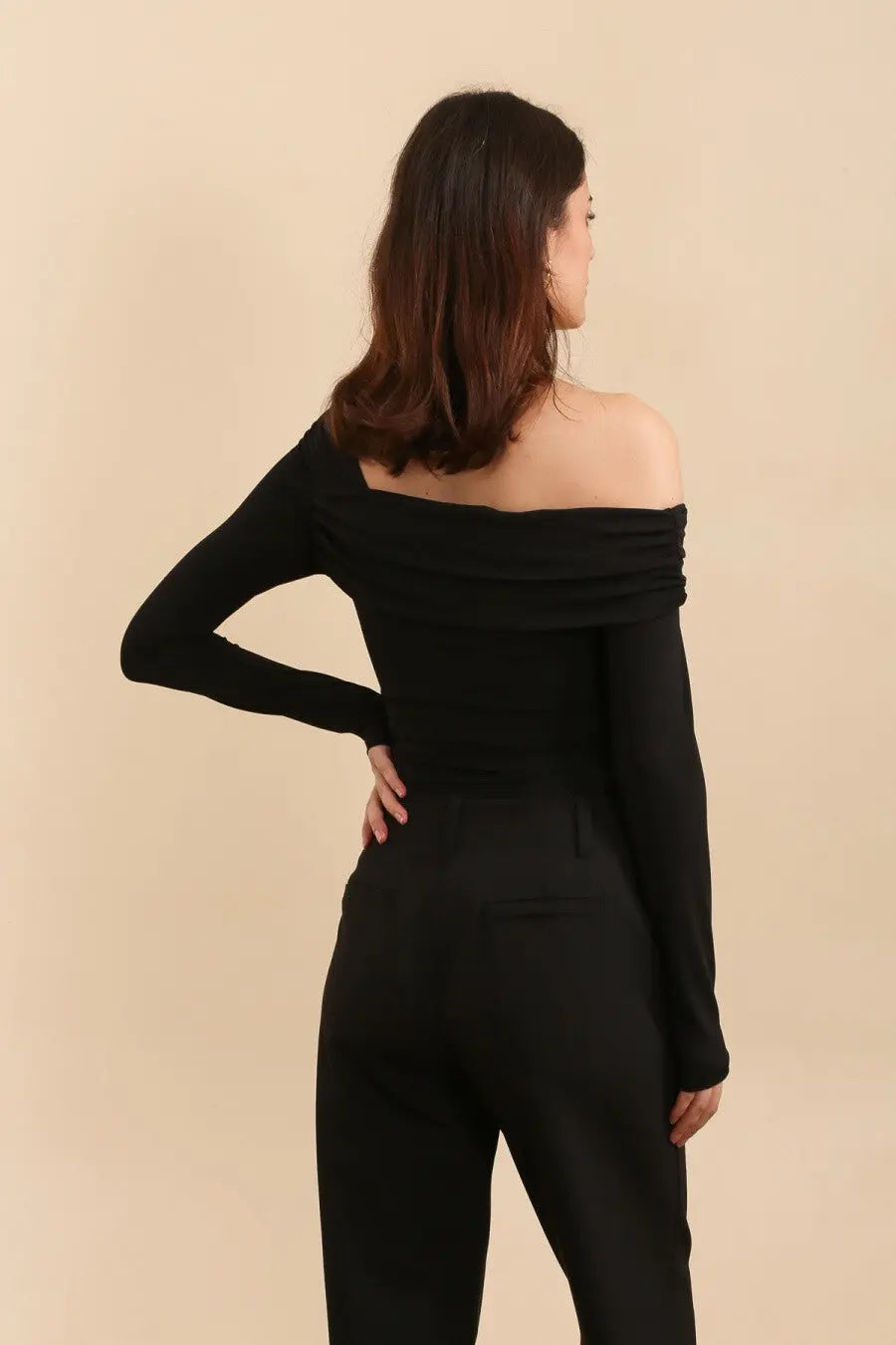 Achterkant zwarte asymmetrische body met een lange mouw en blote schouder. Aansluitende pasvorm van stretchstof. Perfect voor iets casuals of feestelijk.