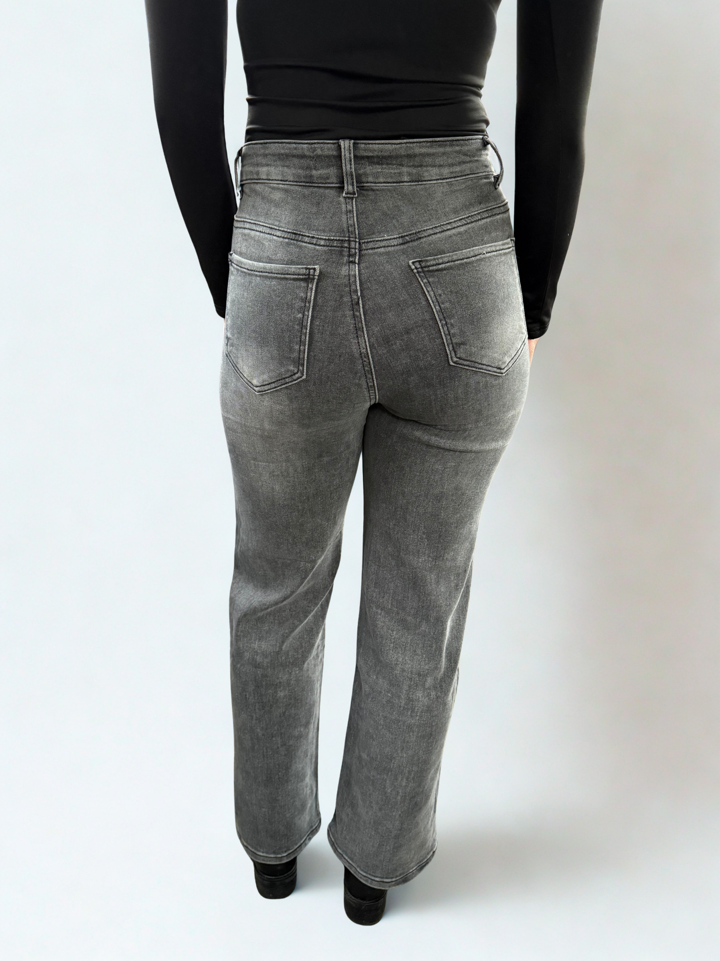Achteraanzicht van een donkergrijze wide leg jeans met opgestikte achterzakken en een relaxte pasvorm, vallend recht over de benen.