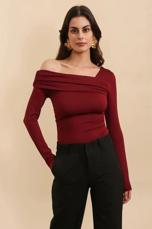 Voorkant bordeaux asymmetrische body met een lange mouw en blote schouder. Aansluitende pasvorm van stretchstof. Perfect voor iets casuals of feestelijk.